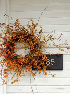 a wreath is hanging on the side of a white building with an address sign in it