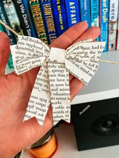 a person holding up a book with a bow on it's ribbon in front of bookshelves