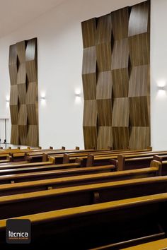 rows of wooden pews lined up against the wall in a large room with white walls