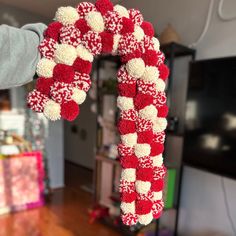 a person holding up a red and white knitted candy cane