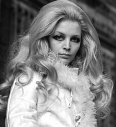 a woman with long blonde hair wearing a fur coat