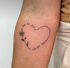 a heart tattoo with the date and flowers on it's left arm is shown