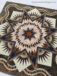 a close up of a quilt on a white table cloth with blue and brown colors