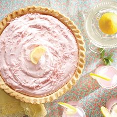 there is a pie with pink icing on it and a lemon wedge next to it