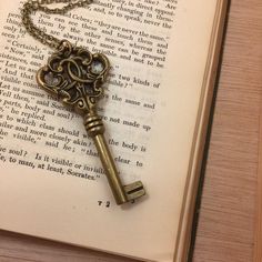 an antique key is sitting on top of an open book