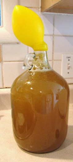 a glass bottle with liquid in it sitting on a kitchen counter next to a tile wall