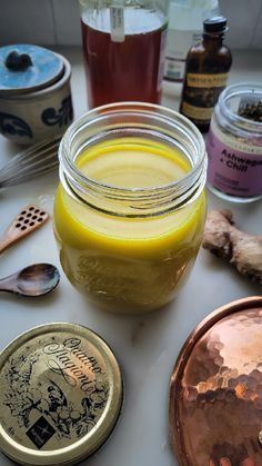 jars filled with liquid sitting on top of a table next to spoons and spices