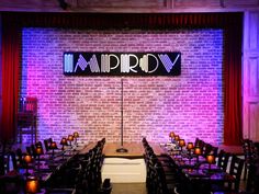 an empty restaurant set up with purple lighting and brick walls, along with candles on the tables