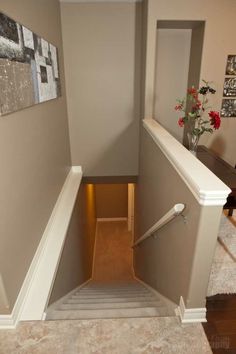 an empty stairway leading up to a room with pictures on the wall and carpeted floor