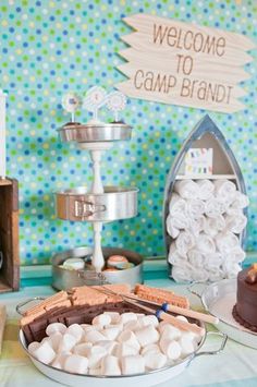 there is a cake and marshmallows on the table with welcome to camp brand sign