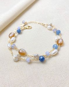 This beautiful layered bracelet showcases a stunning mix of blue and copper gems. The bold mix of gems creates a unique and eye-catching design, while the addition of smooth and baroque pearls adds a touch of elegance. With an adjustable lobster clasp and extender chain, this bracelet offers a perfect fit for anyone lo Elegant Blue Multi-strand Bracelets, Blue Pearl Bracelets For Jewelry Making, Blue Multi-strand Gemstone Beads Bracelets, Blue Multi-strand Bracelets With Gemstone Beads, Blue Pearl Bracelet With Natural Round Beads, Adjustable Blue Pearl Bracelet With Gemstone, Adjustable Blue Pearl Bracelet With Natural Stones, Blue Pearl Bracelet With Natural Stones, Blue Gemstone Pearl Bracelet For Gift