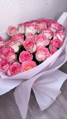 a bouquet of pink roses is wrapped in white paper