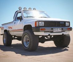 a white truck parked on top of a sandy beach