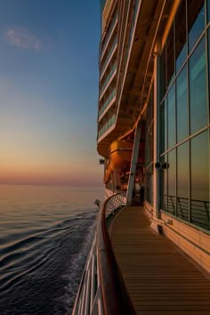 the deck of a cruise ship as the sun sets over the ocean in the distance