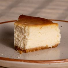 a piece of cheesecake sitting on top of a white and brown plate next to a fork