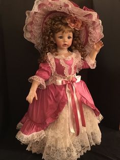 the doll is wearing a pink dress and hat with white lace on it's head