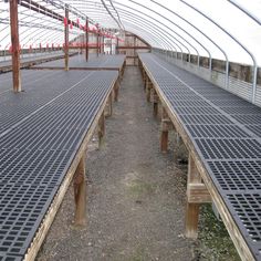 the inside of a large greenhouse with rows of wooden slats on each side and metal grates in between them