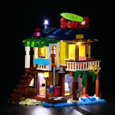 a lego lit up house with lights on it's roof and balcony, in the dark