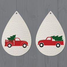 two red trucks with christmas trees on them are hanging from the side of a wooden wall