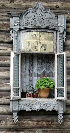 an old window with potted plants in it on the side of a wooden building