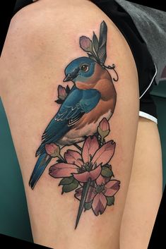 a blue bird sitting on top of a flower next to a person's leg