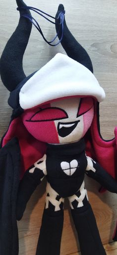 a black and white stuffed animal wearing a red hat on top of a wooden floor