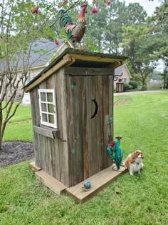 a dog standing in front of a wooden bird house with roosters on the roof