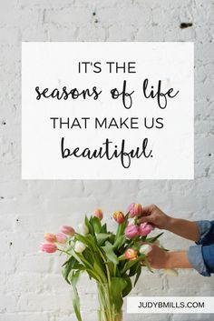 a woman arranging flowers in a vase with a quote on it that reads, it's the seasons of life that make us beautiful