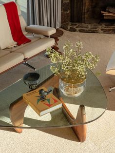 a glass table topped with a book next to a couch and chair in a living room