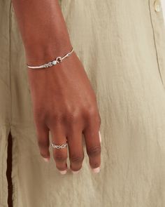 a woman's hand wearing a silver bracelet with an anchor on the wrist and a diamond clasp