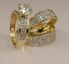 two gold wedding rings with white diamonds on each one and an engagement ring in the middle