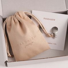 an open box containing a pair of earrings and a card with the word pandasew written on it