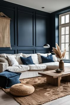 a living room with dark blue walls and white couches, rugs and pillows