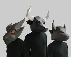 three people wearing masks with horns on their heads, one in black and the other in grey