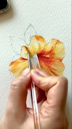 a person is painting a flower with watercolors