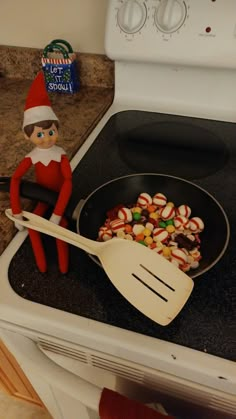 an elf cooking candy in a frying pan on top of the stove with a spatula