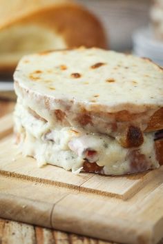 a close up of a sandwich on a wooden cutting board with bread in the background