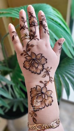 a woman's hand with henna tattoos on it and flowers painted on the palm