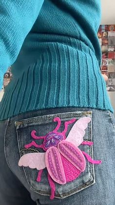 the back of a woman's jeans with an embroidered beetle on it and pink wings