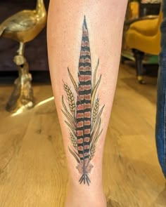 a close up of a person's leg with a tattoo on it that has an image of a feather