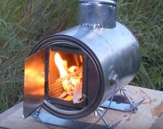 an open fire pit sitting on top of a cement block in front of some grass