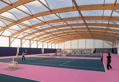 an indoor tennis court with people playing on it