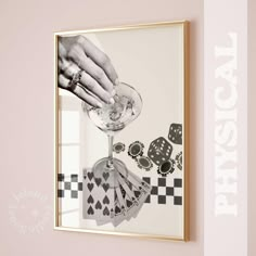 a person holding a wine glass in front of a framed photo with playing cards on it