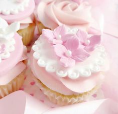 cupcakes decorated with pink and white frosting on top of a pink table cloth