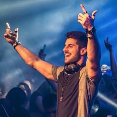 a man holding his hands up in the air at a music concert with other people