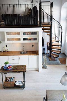 a living room filled with furniture and a spiral stair case in front of a kitchen