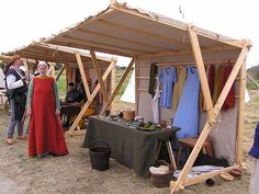 several people standing around a tent with clothes on it