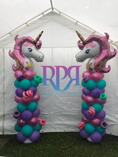 two unicorn balloons are standing next to each other in front of a tent with the letters rrp on it