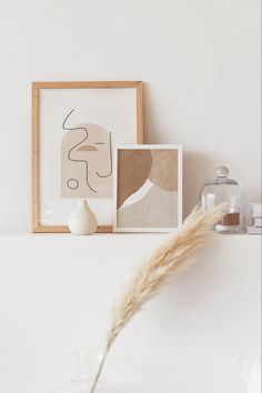 a white shelf with some pictures on it and a vase in front of the wall