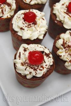 chocolate cupcakes topped with whipped cream and cherries